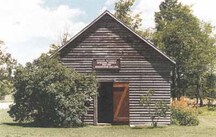 View of the main entrance of the Oro African Methodist Episcopal Church, showing its squared-log, solid wall construction, wood shingle roof, and the wood detailing of the doors, 1999.; Parks Canada Agency / Agence Parcs Canada, Owen Thomas, 1999.