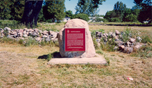 Vue générale de la plaque commémorative et les murs en pierre qui délimitent le lieu historique national du Canada Fort-Sainte-Marie-II, 1989.; Parks Canada Agency / Agence Parcs Canada, 1989.