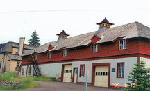 Corner view of the north elevation of the Service Building showing the shingled hip roof with a broad overhang and carved brackets, decorated roof ventilators, dormers and cut-away eaves over the windows, 1995.; Parks Canada Agency / Agence Parcs Canada, C. Zacconi, 1995.