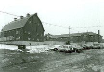 Vue arrière de la petite étable à bovins laitiers, qui montre de nombreuses et grandes fenêtres, et les tourelles carrées sur le toit, 1987.; Parks Canada Agency / Agence Parcs Canada, 1987.