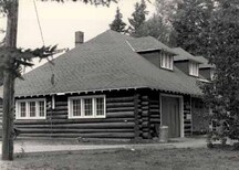 View of the Wardens' Equipment Building, showing the walls of peeled log construction and the exposed rafter ends, 1984.; Agence Parcs Canada / Parks Canada Agency, 1984.