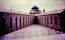 General view of the north wing (left) and Northeast wing (right) of the Saint-Vincent-de-Paul Penitentiary showing the caged gate apertures.; Parks Canada Agency / Agence Parcs Canada, n.d.