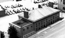 Aerial view of the Old Custom House, showing the low-pitched hipped-roof, accentuated by a broad, symmetrical end chimney, 1994.; Parcs Canada | Parks Canada, 1994.
