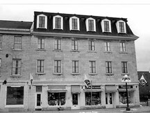 Façade de l'édifice commercial, qui montre le plan de la façade principale sur la promenade Sussex, qui présente trois entrées et trois vitrines de magasin au rez-de-chaussée, 1986.; Parks Canada | Parcs Canada, D. Johnson, 1986.