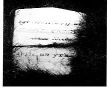 Historic photo of the headstone of the first settler of Cow Head, Mary Payne.  Inscription reads,"In memory of Mary Payne who died ... age 69 years".; HFNL 2005.