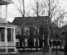 This photo, taken c1912, shows the Cleveland house in the distance.  The dark paint colour is quite a contrast to its current white finish.; Moncton Museum