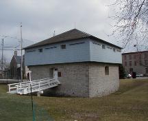 Corner view of the Merrickville Blockhouse, also showing vestiges of former defensive ditch around the building, 2004.; Parks Canada Agency / Agence Parcs Canada, 2004.