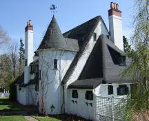 Cette photographie montre la vue contextuelle de l'édifice. Elle montre aussi la tourelle, les cheminées en brique agrémentées de stucco et le toit en imitation chaume, 2007; Town of St. Andrews