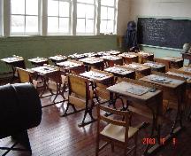 Interior view of Lochiel School showing school desks, blackboard and large windows.; Township of Langley, Julie MacDonald, 2003.