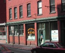 Photograph displaying the storefront and detailing the cast iron pillars, storefront cornice, entrance, and window designs; City of Saint John 2004