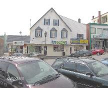 Photo of the front façade of the building which presently houses Greco Pizza Donair. This photo was taken in front of Hutman's Store in downtown Edmundston.; Madawaska Historical Society