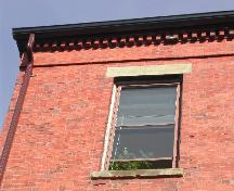 This photograph shows the roof-line cornice with dentils and upper floor window, 2004; City of Saint John