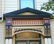 Cette photographie montre le le fronton au-dessus de l'entrée, les consoles ornées et la frise décorative, 2005; City of Saint John