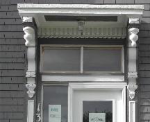 This photograph shows the entrance with ornate entablature, long ornate brackets, pendant finials, and transom window, 2005; City of Saint John