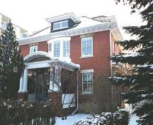 This image illustrates the two-storey north and west brick-clad facades of the George Durrand Residence with prominent Edwardian-era features such as symmetrical composition and the classically influenced front veranda.; City of Edmonton, 2004