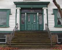 This image provides a view of the prominent central entry consisting of a large entablature supported by wooden Ionic columns, a transom window, side lights and paired wood doors with glass panels, 2005; City of Saint John