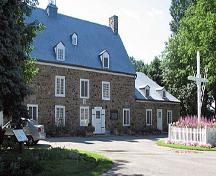 Vue de l'extérieur de la maison Saint-Gabriel, qui montre l'appentis est et la croix de bois, 2005.; Parks Canada Agency / Agence Parcs Canada, N. Clerk, 2005.