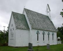 Cette image illustre le toit élevé et pentu ayant à son sommet une délicate cloche dans une arcade en tiers-point et les quatres fenêtres étroites à ogive simple du côté nord de l'édifice. ; PNB 2005