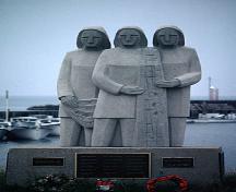 Cette image montre le monument commémoratif, le quai animé des pêcheurs, ainsi que la vue sur le golfe Saint-Laurent.; PNB 2005