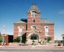 View of the exterior of Fredericton City Hall, showing its Second Empire style, defined by its high hipped roof, central clock tower and projecting entrance portico.; Parks Canada Agency / Agence Parcs Canada.