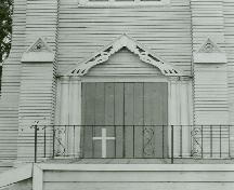 Detail view of Saint Paul's Roman Catholic Church, showing its clapboard cladding and the wooden, twin pilaster surrounds at one of the principal doorways.; Parks Canada Agency / Agence Parcs Canada.