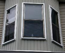 This image shows vertical sliding wood windows in semi-octagonal two-storey bay; City of Saint John
