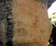 Close-up of recent graffiti and red staining on rock face, 1999.; Government of Saskatchewan, Marvin Thomas, 1999.