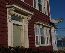 Cette image montre une vue en angle de la porte et la fenêtre principale avec consoles en volute au-dessus des entablements; City of Saint John