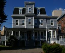 This image shows the symmetrical massing, the mansard roof, the central tower, the wooden shiplap siding and the quoins; City of Saint John