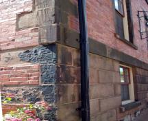 This image shows the stone quoins in brick masonry and the ashlar masonry foundation with chiselled face; City of Saint John