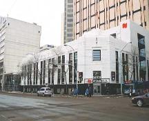 Illustrates the low two and one-half storey massing influenced by the Moderne Stripped Classicism style. Note prominent corner entrance and black granite exterior wainscott band with white cast terrazzo upper cladding.; City of Edmonton, 2004