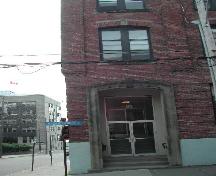 This photograph shows the recessed entranceway, large transom window, and the segmented sandstone arch with keystone, 2004.; City of Saint John