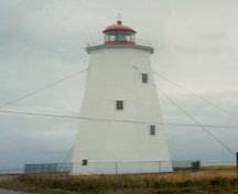 General view of Miscou Island National Historic Site of Canada, showing its colour scheme characteristic of lighthouses and its polygonal lantern set behind a cast iron rail, 1990.; Agence Parcs Canada / Parks Canada Agency, Ministry of Transport, 1990.