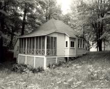 Vue de l'extérieur du chalet des invités, qui montre la charpente en bois revêtue d’un parement de planches horizontales, 1984.; Parks Canada Agency / Agence Parcs Canada, M. Trépanier, 1984.
