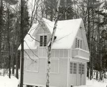 Vue de la façade du garage et domicile des domestiques, qui montre la charpente en bois revêtue d’un parement de planches à mi-bois et de planches en bois posées en quadrillage à l’étage.; Parks Canada Agency / Agence Parcs Canada.
