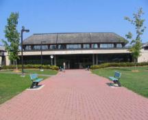 View of the entrance of Block 1300, showing the flat concrete roof supported by concrete columns that project over the entry, to create a deep bay backed by a wall of glass, 2005.; Parks Canada Agency / Agence Parcs Canada, Kate MacFarlane, 2005.