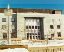 View of the main entrance to the Federal Building in Sherbrooke, showing accent features inspired by Art Deco design such as the copings, curved entrance returns and ribbed canopy projections, 1995.; Public Works and Government Services Canada / Travaux publics et Services gouvernementaux Canada, 1995.