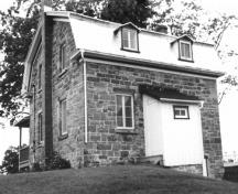 Rear view of the Collector's House, showing its exterior walls of squared stone masonry, terminating in quoins, 1989.; Parks Canada Agency / Agence Parcs Canada, 1989.