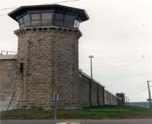 Vue de la tour D-4, qui montre la base en béton évasée des tours de garde, et le fût en pierre octogonal, 1990.; Correctional Services Canada / Service correctionnel du Canada, 1990.