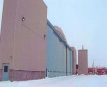 Vue générale du hangar 6, qui montre les vastes portes coulissantes qui permettent le passage des appareils et leur rang horizontal de petites ouvertures à hauteur d’homme, 2006.; Department of National Defence / Ministère de la Défense nationale, 2006.