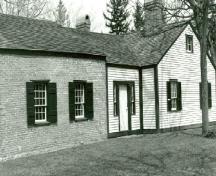 Side view of the Junior Commissariat Officer's Quarters, showing the shuttered multi-pane windows, ca. 1989.; Parks Canada Agency / Agence Parcs Canada, ca./vers 1989.