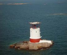 General view of Red Rock Light Tower, showing the contrasting textures and colors between the red riveted steel plates of the base and the smooth white concrete walls above.; Canadian Coast Guard / Garde côtière canadienne.