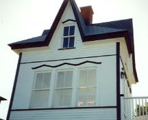 Detail view of Cabin 1, showing the tall dormers whose ridges meet in the centre where the chimney rises.; Parks Canada Agency / Agence Parcs Canada.