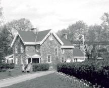 View of the exterior of the Superintendent's House, showing the two-and-a-half-storey massing, and the gable roof with chimneys, 1985.; Parks Canada Agency / Agence Parcs Canada, 1985.