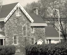 Vue d'une façade de la résidence du surintendant, qui montre les murs extérieurs en pierres de grès posées en assises irrégulières, 1985.; Parks Canada Agency / Agence Parcs Canada, 1985.