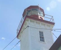 General view of East Ironbound Combined Lighthouse and Dwelling, showing the decorative bracketed cornice supporting the square wood platform and octagonal, cast-iron lantern, 2005.; Public Works and Government Services Canada / Travaux publics et Services gouvernementaux Canada, Don MacDonald, 2005.