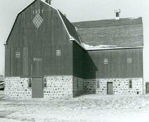 General view of the Barn, showing the L-shaped gambrel-roofed structure built of stone and timber, 1988.; Agence Parcs Canada, Homestead Motherwell/ Parks Canada Agency, Motherwell Homestead, 1988.