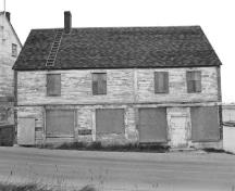 View of the main façade of the Ryan Retail Store, showing the pattern and size of window and door openings and the clapboard walls that are outlined by finely proportioned trim, 1991.; Agence Parcs Canada / Parks Canada Agency, 1991.