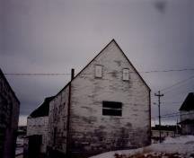 Northwest façade of the Ryan Store and Fish Purchasing Centre, showing the two-storey, box-like form capped with a side-gable roof, 1993.; Agence Parcs Canada / Parks Canada Agency, 1993.