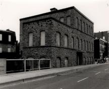 View of the East Mill, showing the regular placement of the doors and evenly spaced windows, 1972.; Agence Parcs Canada / Parks Canada Agency, 1972.